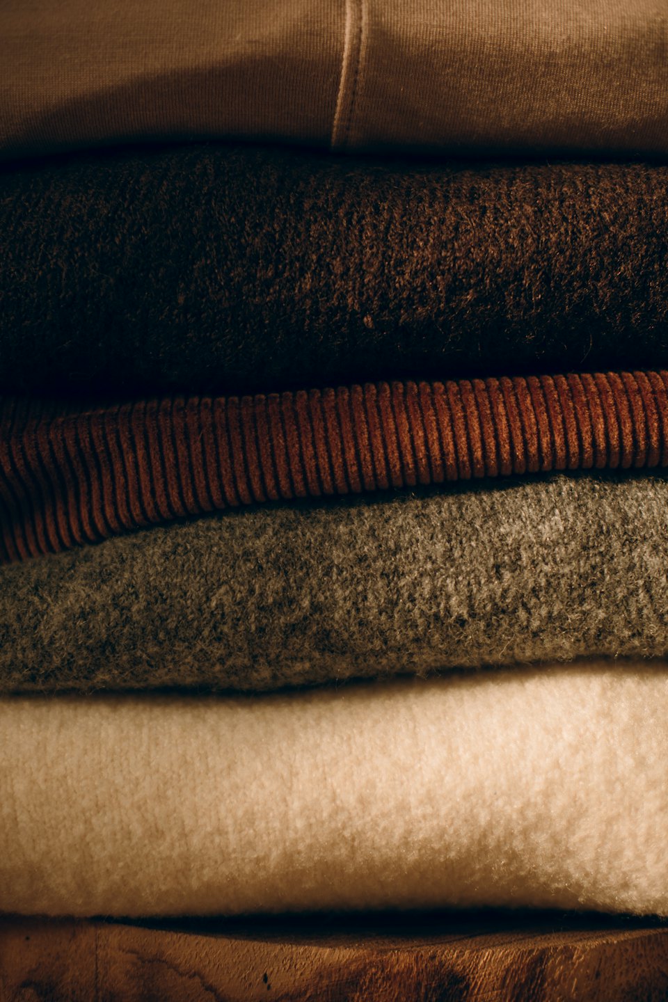 A stack of neatly folded clothing with diverse fabric textures.